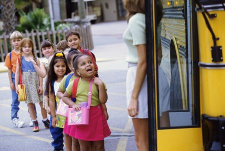 małe dzieci wsiadają do autobusu wycieczka szkolna w czasie upału